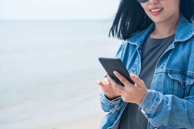 Vrouw gebruikt smartphone op strand.