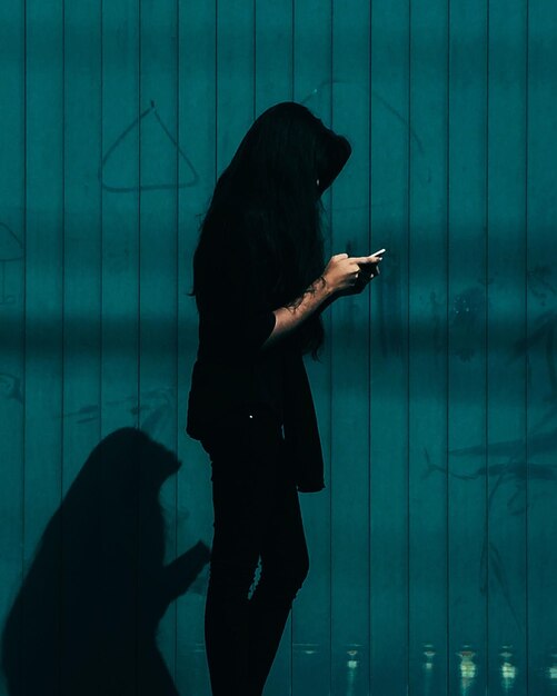 Foto vrouw gebruikt smartphone tegen blauwe muur