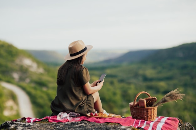 vrouw gebruikt telefoon bij picknick