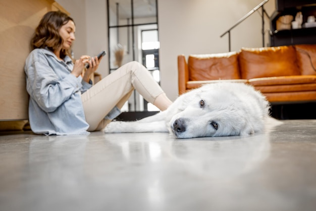 Vrouw gebruikt telefoon door hond terwijl ze op de vloer zit