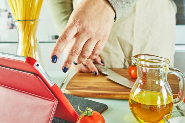 Vrouw gebruikt vingerdia op tabletscherm koken volgens de tutorial van online virtuele masterclass,