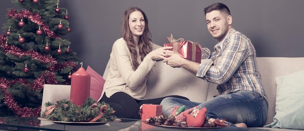 Foto vrouw geeft geschenk aan man tijdens kerstmis