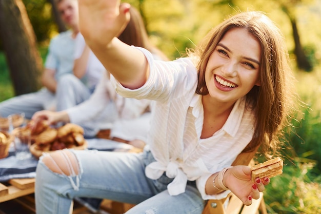 Vrouw geeft high five aan fotograaf Groep jongeren hebben vakantie buiten in het bos Conceptie van weekend en vriendschap