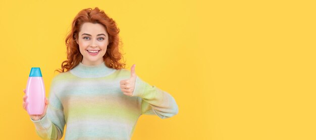 Foto vrouw geïsoleerd gezicht portret banner met kopie ruimte gelukkige roodharige vrouw met krullend haar met shampoo of conditioner met duim omhoog kapper