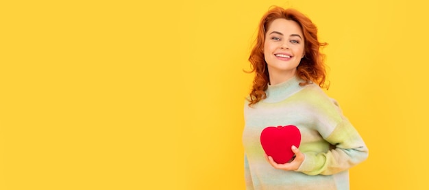 Vrouw geïsoleerd gezicht portret banner met kopie ruimte vrolijke roodharige vrouw met rood hart op gele achtergrond love