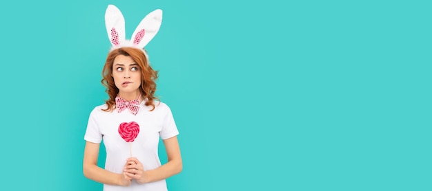 Vrouw geïsoleerd gezicht portret banner met mock-up copyspace bang pasen vrouw dragen konijnenoren houden hart lollipop