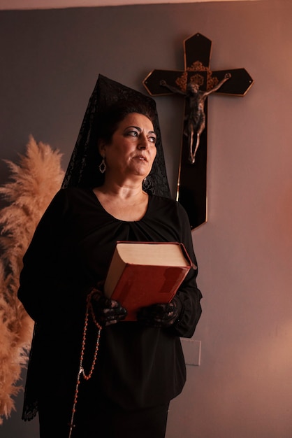 Vrouw gekleed in het zwart met een bijbel en een rozenkrans in haar hand