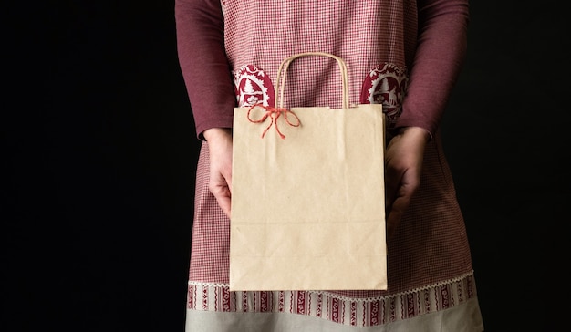 Vrouw gekleed in rode feestelijke schort met boodschappentas aan de vooravond van het nieuwe jaar.