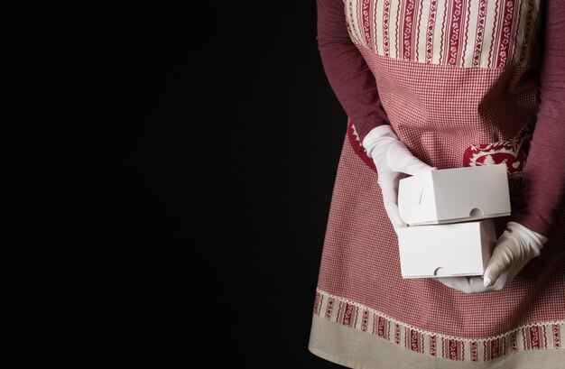 Vrouw gekleed in rode feestelijke schort met geschenkdozen aan de vooravond van nieuwjaar.