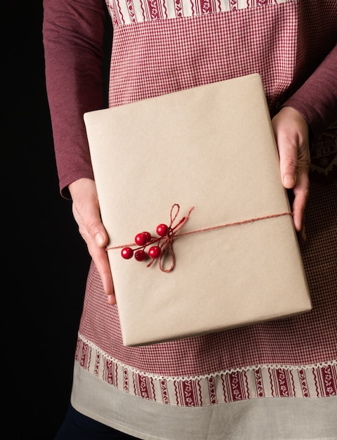 Vrouw gekleed in rode feestelijke schort met Gift's Box aan de vooravond van Nieuwjaar.