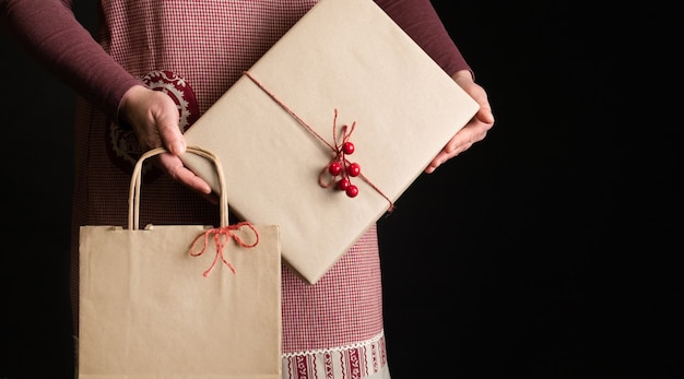 Vrouw gekleed in rode feestelijke schort met Gift's Box en boodschappentas aan de vooravond van Nieuwjaar.