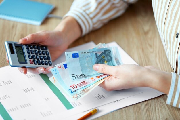 Foto vrouw geld tellen en bezig met rekenmachine aan tafel