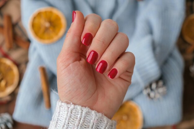 Vrouw gemanicuurde handen stijlvolle rode nagels kopiëren ruimte Blauwe trui Close-up Winter- of herfststijl van nagelontwerpconcept Schoonheidsbehandeling