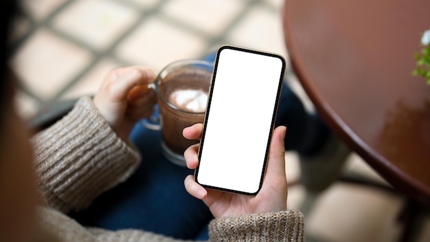 Vrouw geniet ervan iets online te kijken via haar smartphone en 's ochtends koffie te drinken