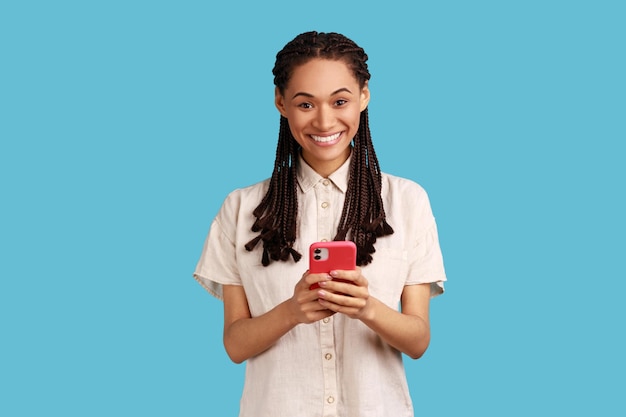 Vrouw geniet van communicatie op afstand gebruikt mobiele telefoon surft onbeperkt internet heeft een aangename glimlach