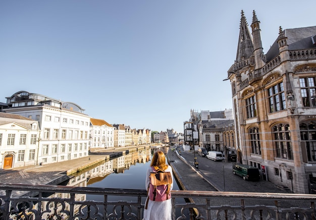 Vrouw geniet van een prachtig uitzicht op het waterkanaal dat achterover staat op de brug in de stad Gent in België