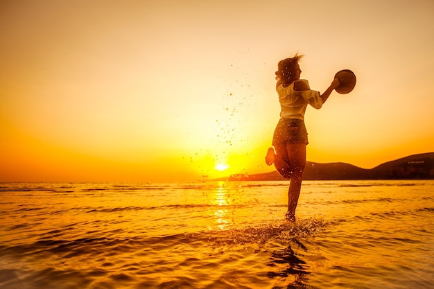 Vrouw geniet van een prachtige zonsondergang op het strand