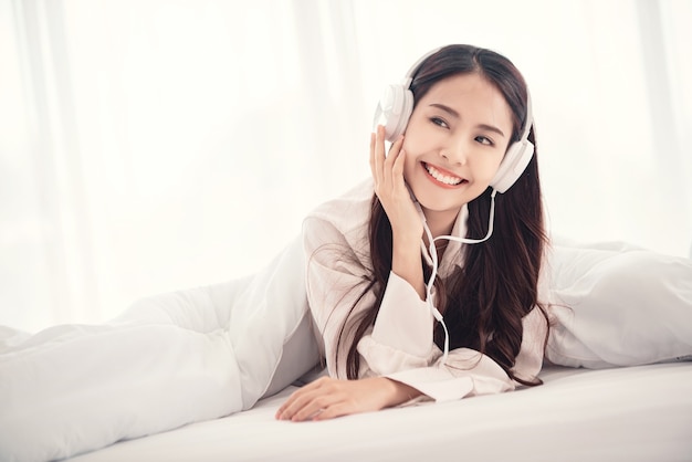 vrouw geniet van het luisteren naar muziek met een hoofdtelefoon in de slaapkamer