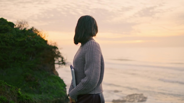 Vrouw geniet van oceaanschemering wandelen op kustheuvel met album sombere natuur