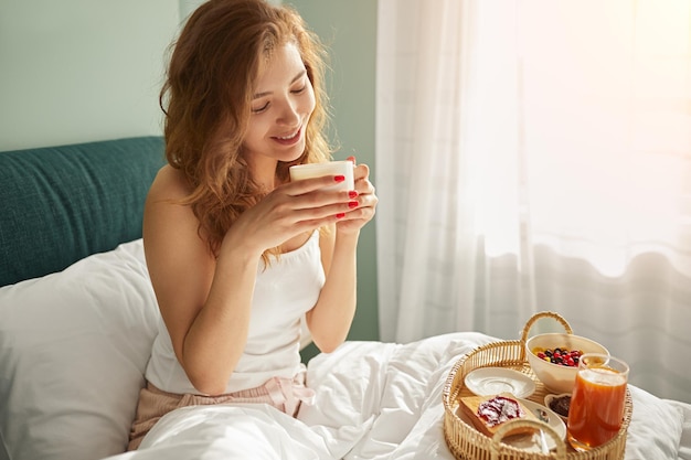 Vrouw geniet van ontbijt op bed