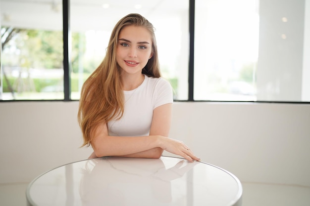 Vrouw geniet van poseren op een minimale witte plek. Minimale witte plaats en achtergrond en mooie blonde blanke dame in het interieur van minimaal café.