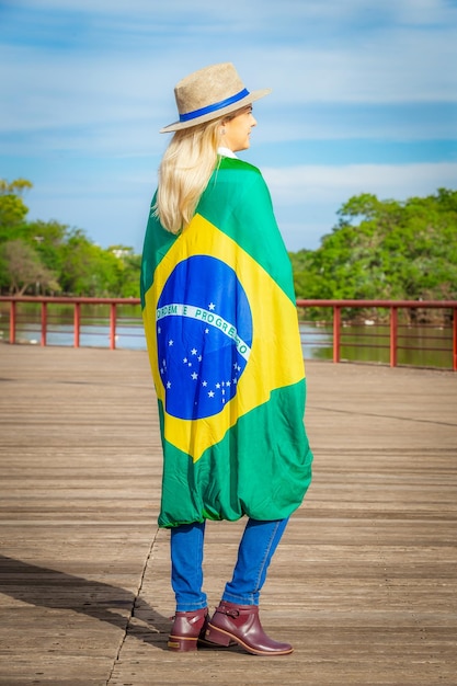 Vrouw gewikkeld in een Braziliaanse vlag met hoed en spijkerbroek Agribusiness woman