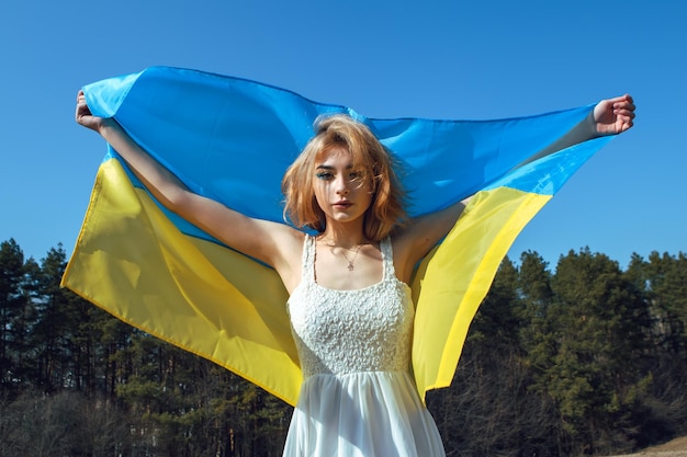 Vrouw gewikkeld in Oekraïense vlag Stand met Oekraïne concept