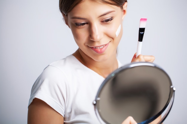 Vrouw gezicht huid cosmetica, vrouw voor een spiegel past een crème voor huidverzorging