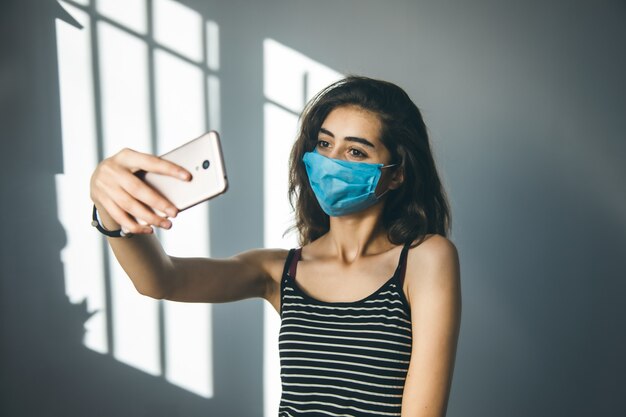 Vrouw gezichtsmasker en hand telefoon selfie op grijs