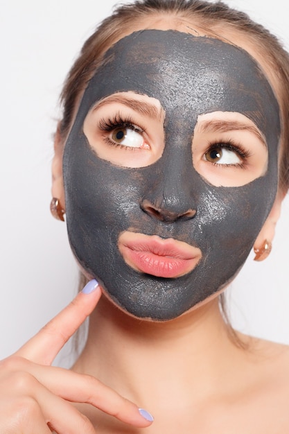 Vrouw gezichtsmasker. Portret van mooi meisje dat cosmetische zwarte peeling masker van de gezichtshuid verwijdert. Close-up van aantrekkelijke jonge vrouw met natuurlijke make-up en cosmetische Peel masker op gezicht. Hoge resolutie