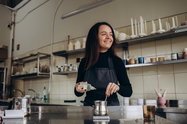 Vrouw giet gesmolten was in amberkleurige kaarsencontainer Ecologisch en veganistisch bedrijf Sojawaskaarsaccessoires Handgemaakt met liefde Werken op afstand online winkel werkplek