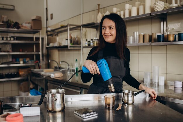 Vrouw giet gesmolten was in amberkleurige kaarsencontainer Ecologisch en veganistisch bedrijf Sojawaskaarsaccessoires Handgemaakt met liefde Werken op afstand online winkel werkplek