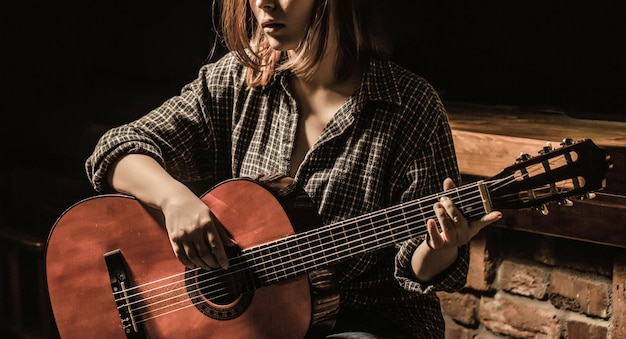 Vrouw gitaar spelen, met een akoestische gitaar in zijn handen. Muziekconcept. Meisje gitarist speelt.