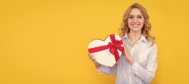 vrouw glimlach met huidige hartdoos op gele achtergrond Vrouw geïsoleerde gezicht portret banner met mock-up kopie ruimte