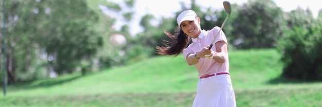 Vrouw golfer met golfclub in de hand en vliegende bal na het raken