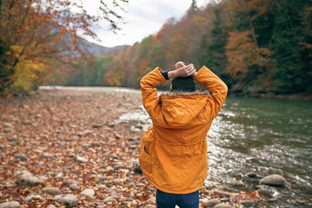 Vrouw gooit haar handen in de natuur Herfst bos rivier gevallen bladeren