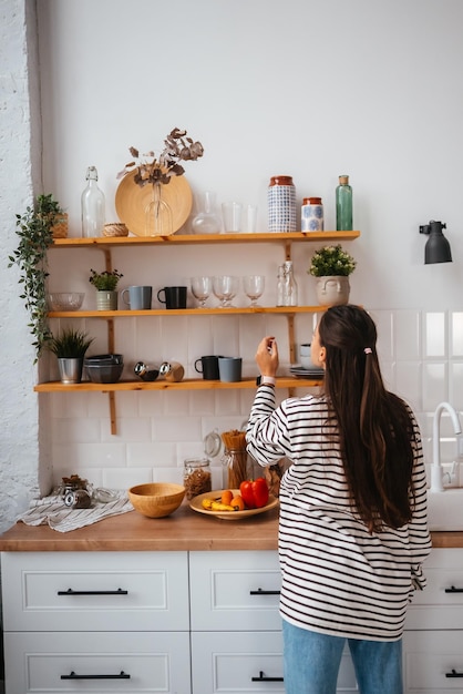 Vrouw haalt een glas uit de plank in de keuken