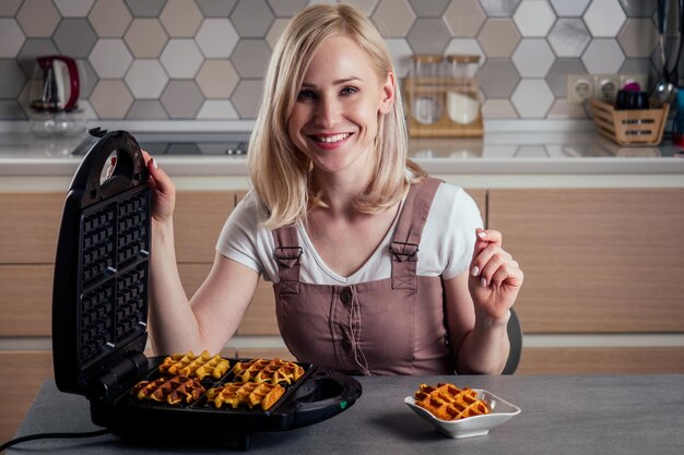 Vrouw haalt verse wafels uit wafelijzer in Belgische keukenwafels