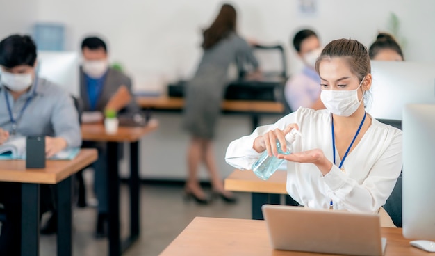 Vrouw haar handen schoonmaken op kantoor. Ziek met masker voor coronavirus.