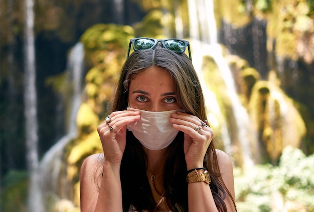 Vrouw haar masker in de natuur opstijgen