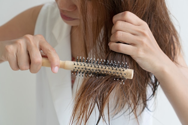 Vrouw haar natte rommelige haren borstelen na bad met kam, dun haar porblem. Haarschade, gezondheid en schoonheid concept.