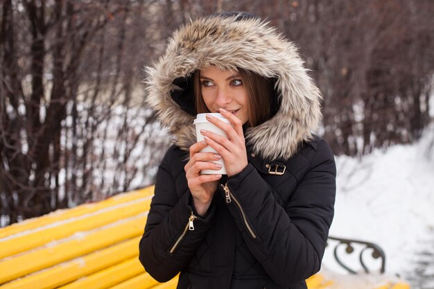 Vrouw haar warme drank drinken uit beker. Winter seizoen.