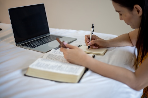 Vrouw hand bidden op heilige bijbel in de ochtend. Bestudeer de bijbel met online aanbidding.