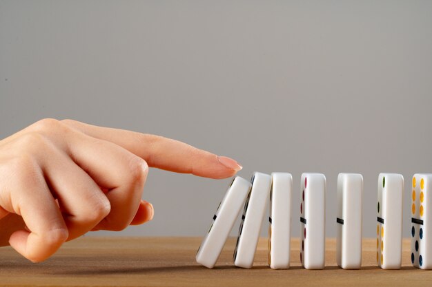 Vrouw hand domino omverwerpen. Kettingreactie bedrijfsconcept