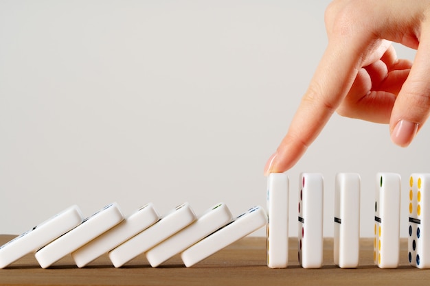 Vrouw hand domino omverwerpen. Kettingreactie bedrijfsconcept