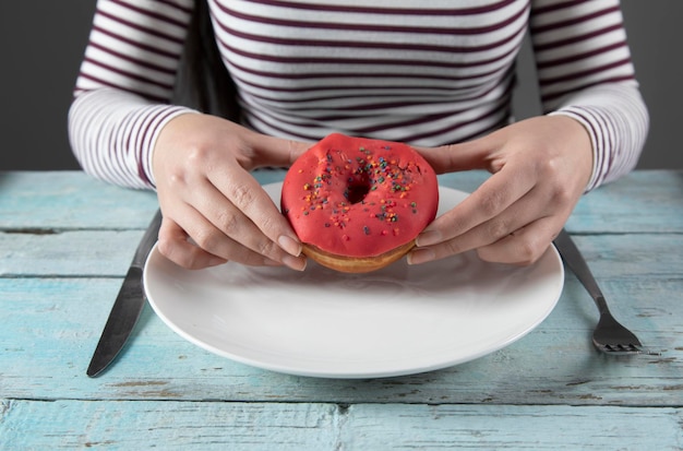 Vrouw hand donut in plaat