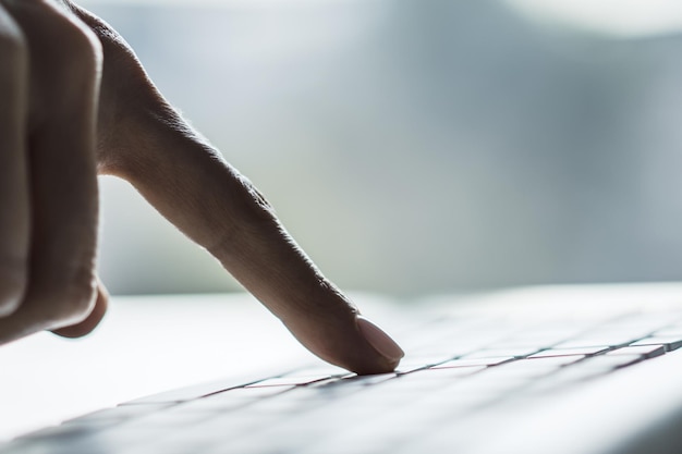 Vrouw hand drukt op een knop op laptop toetsenbord close-up