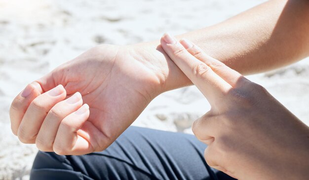 Vrouw hand en pols hartslag en pols controleren met vinger buiten na training of cardio Persoon handen en hartslag controleren na gezonde training of lichaamsactiviteit in de natuur op het strand