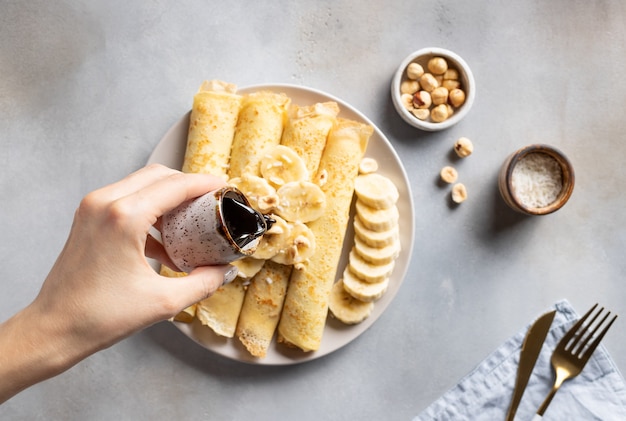 Vrouw hand giet dadelsiroop over dunne bananenpannenkoekjes