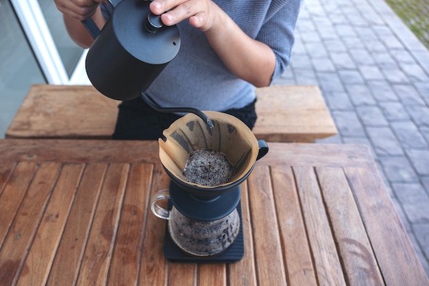 vrouw hand gieten heet water om een infuus koffie te maken op vintage houten tafel